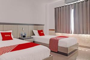 pokój hotelowy z 2 łóżkami i czerwonymi poduszkami w obiekcie OYO 92518 De Luna Hotel w mieście Banjarbaru