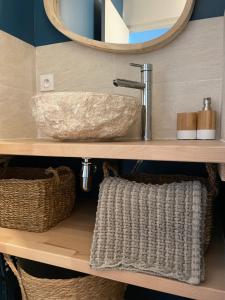 een badkamer met een wastafel, een spiegel en manden bij « Le Bellevue » by P&T in Canet-en-Roussillon