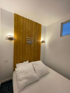 een slaapkamer met een wit bed en een houten muur bij « Le Bellevue » by P&T in Canet-en-Roussillon