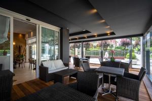 a living room with chairs and tables and windows at Hotel Mocambo in Riccione