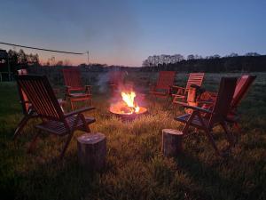 grupa krzeseł wokół ogniska na polu w obiekcie Rest in Manowo - Holiday Home Baltic Sea w mieście Manowo