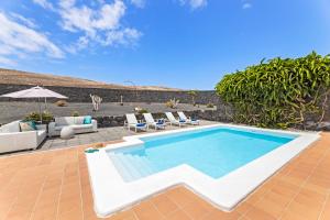 a swimming pool with lounge chairs and an umbrella at Villalia Nerea in Playa Blanca