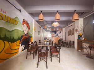 a restaurant with a large painting on the wall and tables and chairs at Bảo Lạc - Sunny Homestay in Bảo Lạc