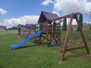 a wooden playground with a slide in a field at Słoneczny Domek in Grywałd