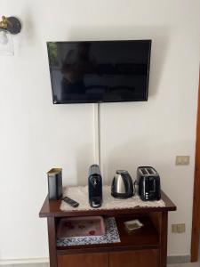 uma televisão numa parede por cima de uma mesa com electrodomésticos em Putzurile House em Orosei