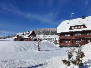 een met sneeuw bedekt gebouw voor een gebouw bij Hotel Sonnenmatte Titisee B und B nahe Badeparadies in Titisee