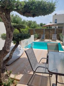 un patio con sillas y un árbol junto a una piscina en Zante Flower Studios & Apartments en Alikanas