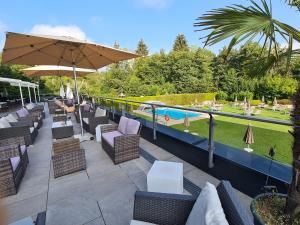 patio z leżakami i parasolami oraz basenem w obiekcie Dei Hotel Schönblick w mieście Velden am Wörthersee