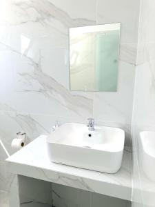 a white bathroom with a sink and a mirror at Falirala Central in Faliraki