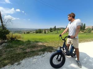 Un uomo in piedi su una bicicletta per strada di Agriturismo il Bacucco a Montecarotto