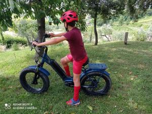 Una joven está montando una bicicleta en el césped en Agriturismo il Bacucco, en Montecarotto