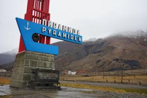 um sinal para uma estação de comboios com montanhas ao fundo em Hotel Pyramiden em Pyramiden