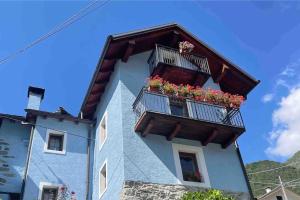 un edificio con due balconi con fiori di CASA DEL CIOS calda e intima casetta immersa nel verde delle montagne a Alpe Basciumo