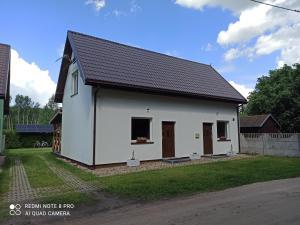 a small white house with a black roof at Apartameny Wiktoria i Nikola w Karwiku in Pisz