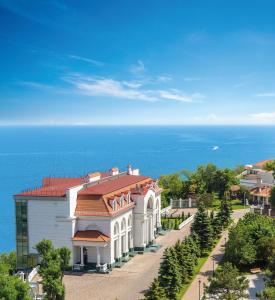 - un bâtiment blanc avec un toit rouge à côté de l'océan dans l'établissement KADORR Hotel Resort & Spa, à Odessa