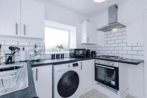 una cocina blanca con lavadora. en SPECIAL RATE FOR BOOKINGS MORE THAN 7 NIGHTS, WARM SPACIOUS CONTRACTOR HOUSE NEAR LIVERPOOL CITY CENTRE SLEEPS 8 kitchen & dining room, washing machine en Liverpool