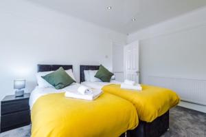 2 camas con sábanas amarillas en una habitación en SPECIAL RATE FOR BOOKINGS MORE THAN 7 NIGHTS, WARM SPACIOUS CONTRACTOR HOUSE NEAR LIVERPOOL CITY CENTRE SLEEPS 8 kitchen & dining room, washing machine en Liverpool