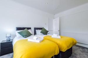 2 Betten mit gelber Bettwäsche in einem Zimmer in der Unterkunft SPECIAL RATE FOR BOOKINGS MORE THAN 7 NIGHTS, WARM SPACIOUS CONTRACTOR HOUSE NEAR LIVERPOOL CITY CENTRE SLEEPS 8 kitchen & dining room, washing machine in Liverpool