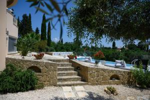 un jardín con una pared de piedra y una piscina en Aeras Luxury Villa, en Kastanéa