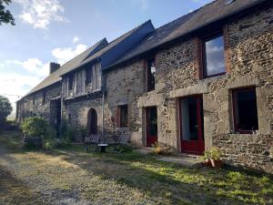 uma antiga casa de pedra com uma porta vermelha em Edel de la Touche Balard em Val Couesnon