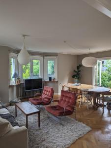 a living room with red chairs and a table at 30-tals villa med närhet till centrala GBG in Gothenburg