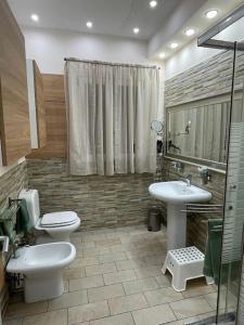 een badkamer met 2 wastafels, een toilet en een douche bij Casa Vacanze di Laura in Zafferana Etnea
