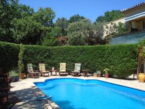 una piscina con sillas y un seto en La Soleillade Laudun, en Laudun