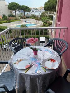 une table avec des assiettes et un vase de fleurs sur le balcon dans l'établissement "Le Pharo" 17 Impasse du globe Appartement, au Cap d'Agde