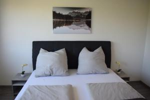 una camera da letto con un letto con lenzuola e cuscini bianchi di Rebekka‘s Apartment a Füssen