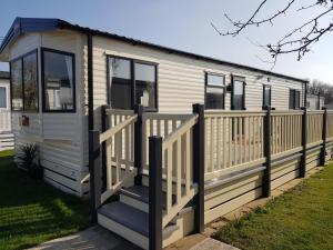 a white tiny house with a wooden fence at 2 Bedroom Lodge, Milford on Sea in Milford on Sea