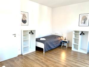 Schlafzimmer mit einem Bett, weißen Wänden und Holzböden in der Unterkunft 2 Rooms, free Parking, 25 min to Düsseldorf, 150 Mbps WLAN in Duisburg