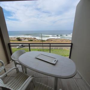 een tafel en stoelen op een balkon met uitzicht op de oceaan bij Driftsands Sea View Flats in Uvongo Beach