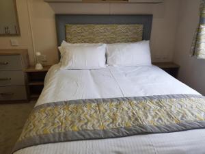 een slaapkamer met een groot bed met witte lakens en kussens bij 2 Bedroom Lodge, Milford on Sea in Milford on Sea