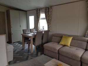 ein Wohnzimmer mit einem Sofa und einem Tisch in der Unterkunft 2 Bedroom Lodge, Milford on Sea in Milford on Sea