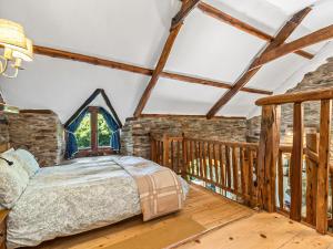 a bedroom with a bed and a wooden balcony at Ysgubor Ganol in Llanglydwen