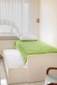 Una cama blanca con una manta verde encima. en Seaside Villa, en Alexandroupoli