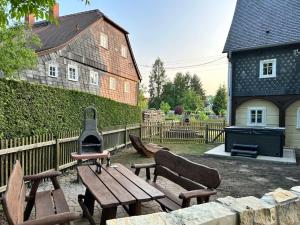 a picnic table and benches with a stove in a yard at Ferienwohnung Ornella mit Sauna, Whirlpool in Großschönau