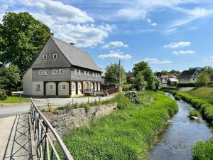 een gebouw naast een rivier met een huis bij Ferienwohnung Ornella mit Sauna, Whirlpool in Großschönau