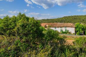a house in the middle of a field with trees at Le Pech Merle YourHostHelper in Saint-Jean-de-Minervois