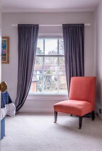 a red chair sitting in front of a window at Beautiful & Spacious Retreat in Winchester in Winchester