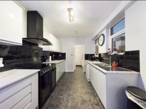 a kitchen with white cabinets and black appliances at Sylvern House in Scarborough