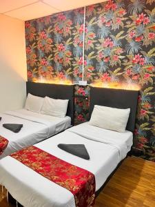 two beds in a room with a floral wallpaper at Hotel Citra in Brinchang