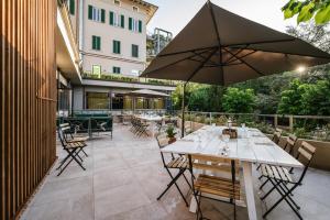 eine Außenterrasse mit Tischen und einem Sonnenschirm in der Unterkunft Palazzo BelVedere in Montecatini Terme