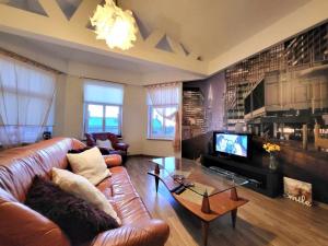 a living room with a leather couch and a television at Riga Centre Sun Apartments in Rīga