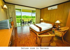 a bedroom with a bed and a television and a balcony at Nazimgarh Garden Resort in Sylhet