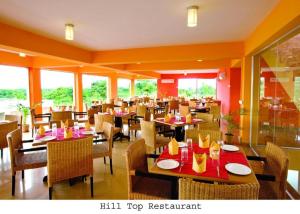 a dining room with tables and chairs and windows at Nazimgarh Garden Resort in Sylhet