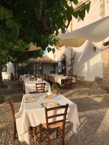 ein Restaurant mit weißen Tischen und Stühlen unter einem Baum in der Unterkunft Fattoria Manostalla Villa Chiarelli in Balestrate