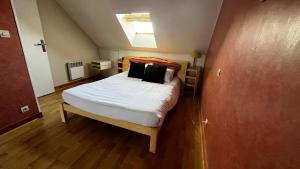 1 dormitorio con 1 cama con sábanas blancas y almohadas negras en Le 24 Clemenceau, en Châtellerault