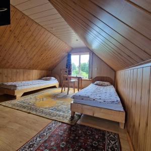 a attic room with two beds and a table at Griežto 5 in Zarasai