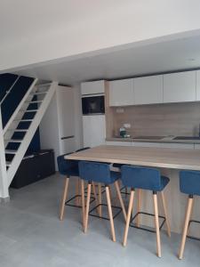 eine Küche mit einem Holztisch und blauen Stühlen in der Unterkunft Appartement dans village vacances in Ghisonaccia